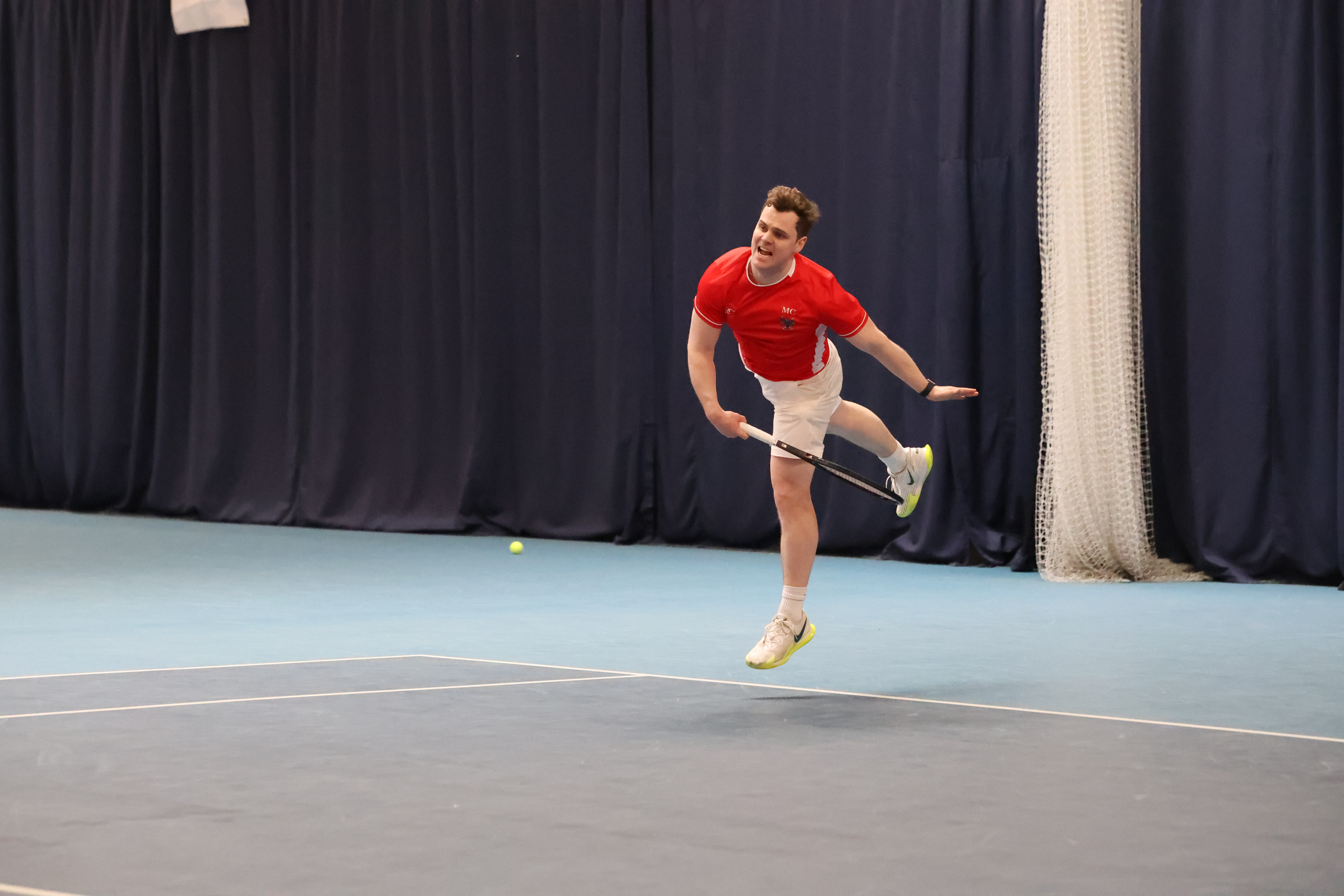 Tennis serving against UCL at varsity.