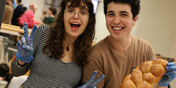 Two students holding a loaf of bread and laughing