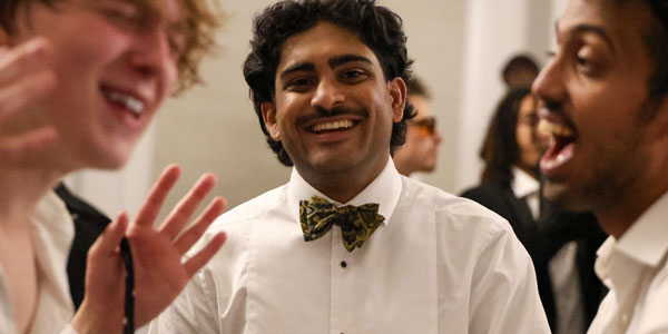 Three students smiling at the camera wearing formal wear at a fancy event