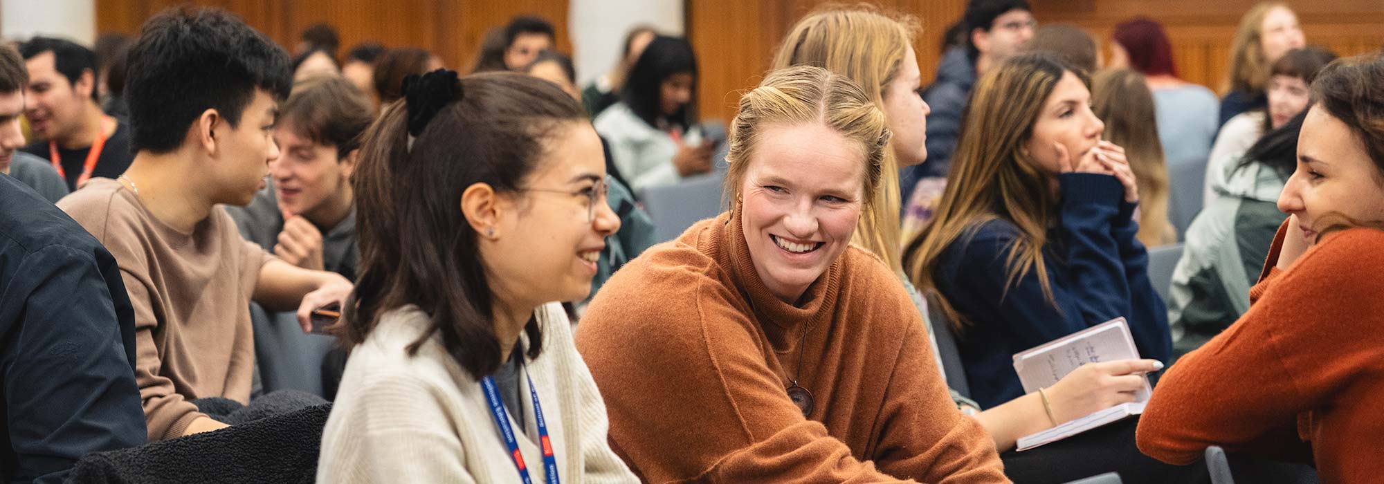 Students talking and smiling to each other in a lecture theatre