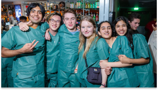 A photograph of a group of students in a bar, wearing blue scrubs
